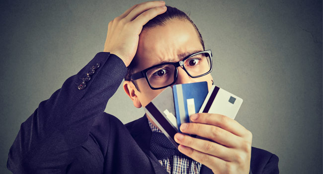 A confused man with three credit cards in his hand Image